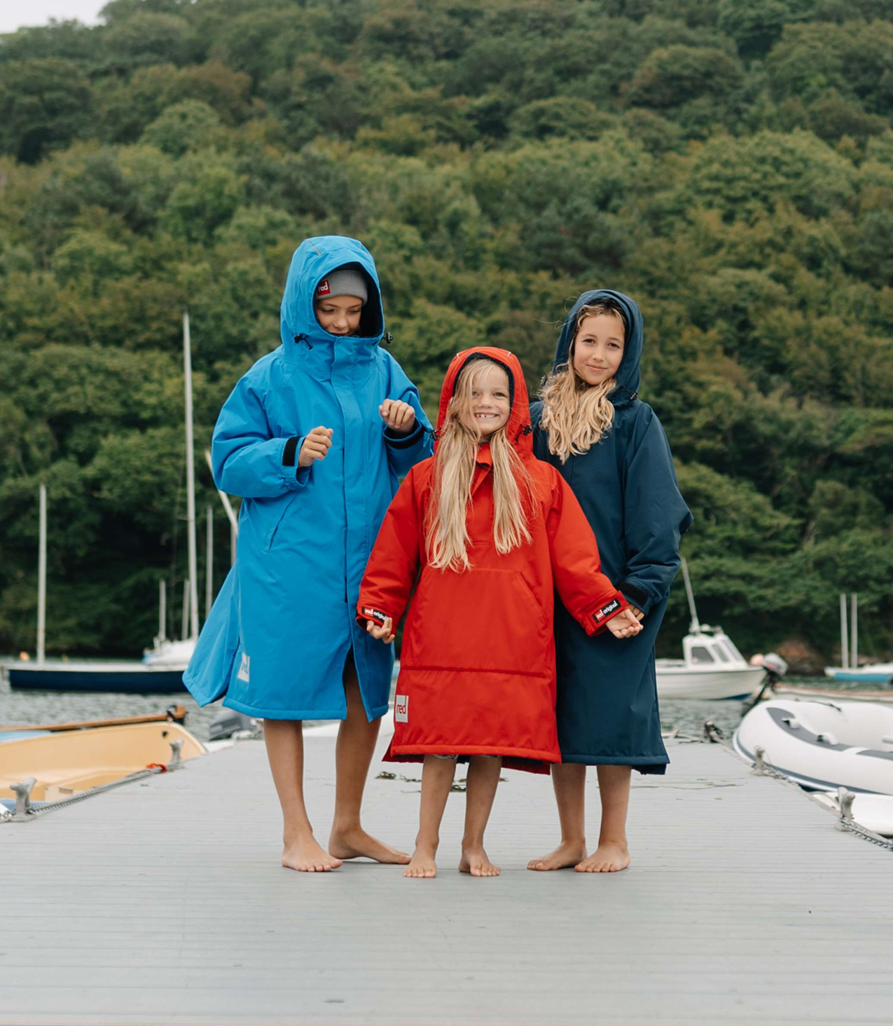 Three children on a dock with waterproof jackets