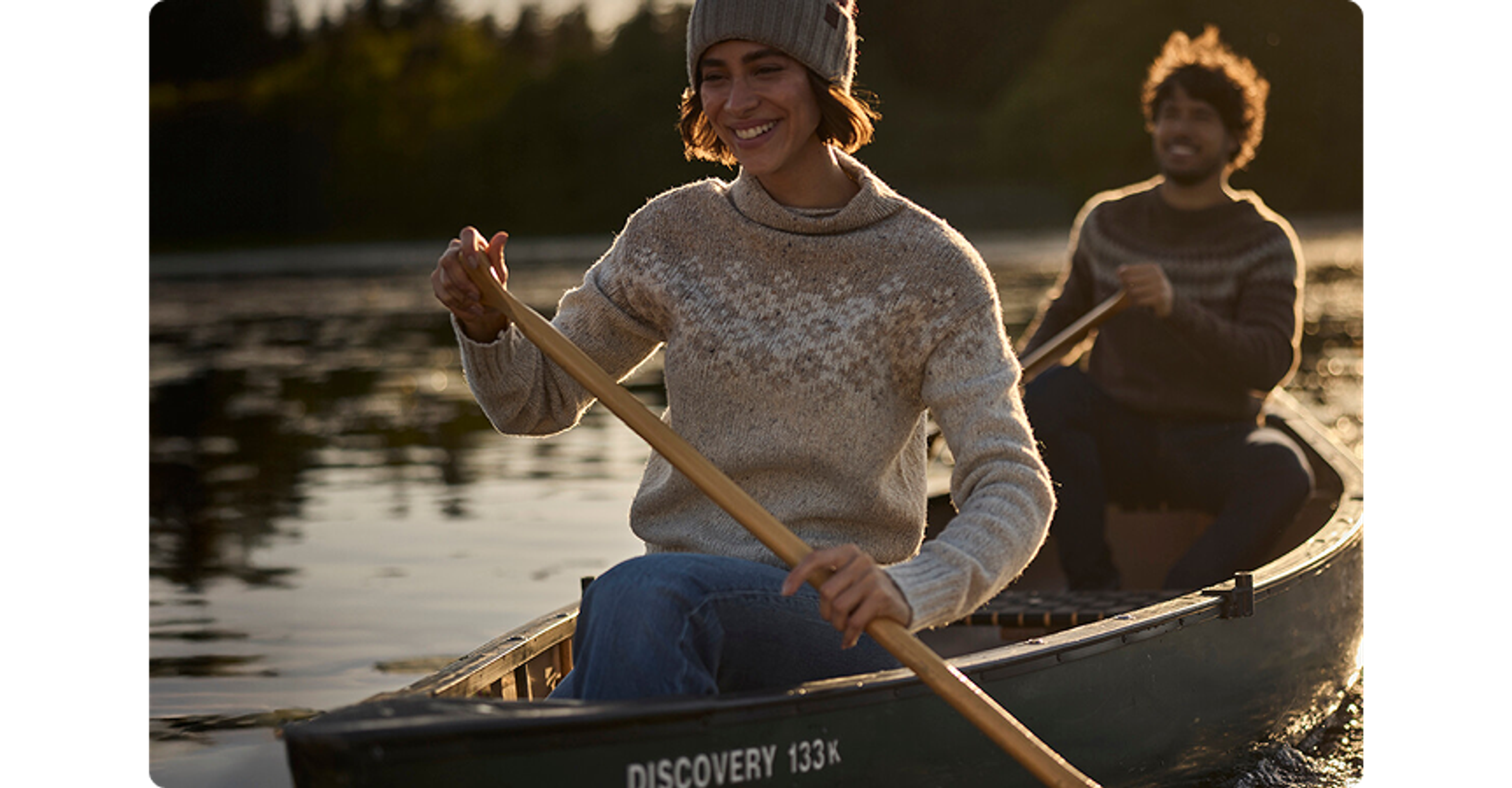 two people paddling in a canoe while smiling