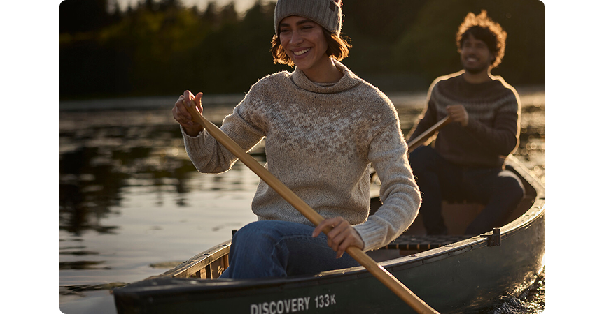 two people paddling in a canoe while smiling
