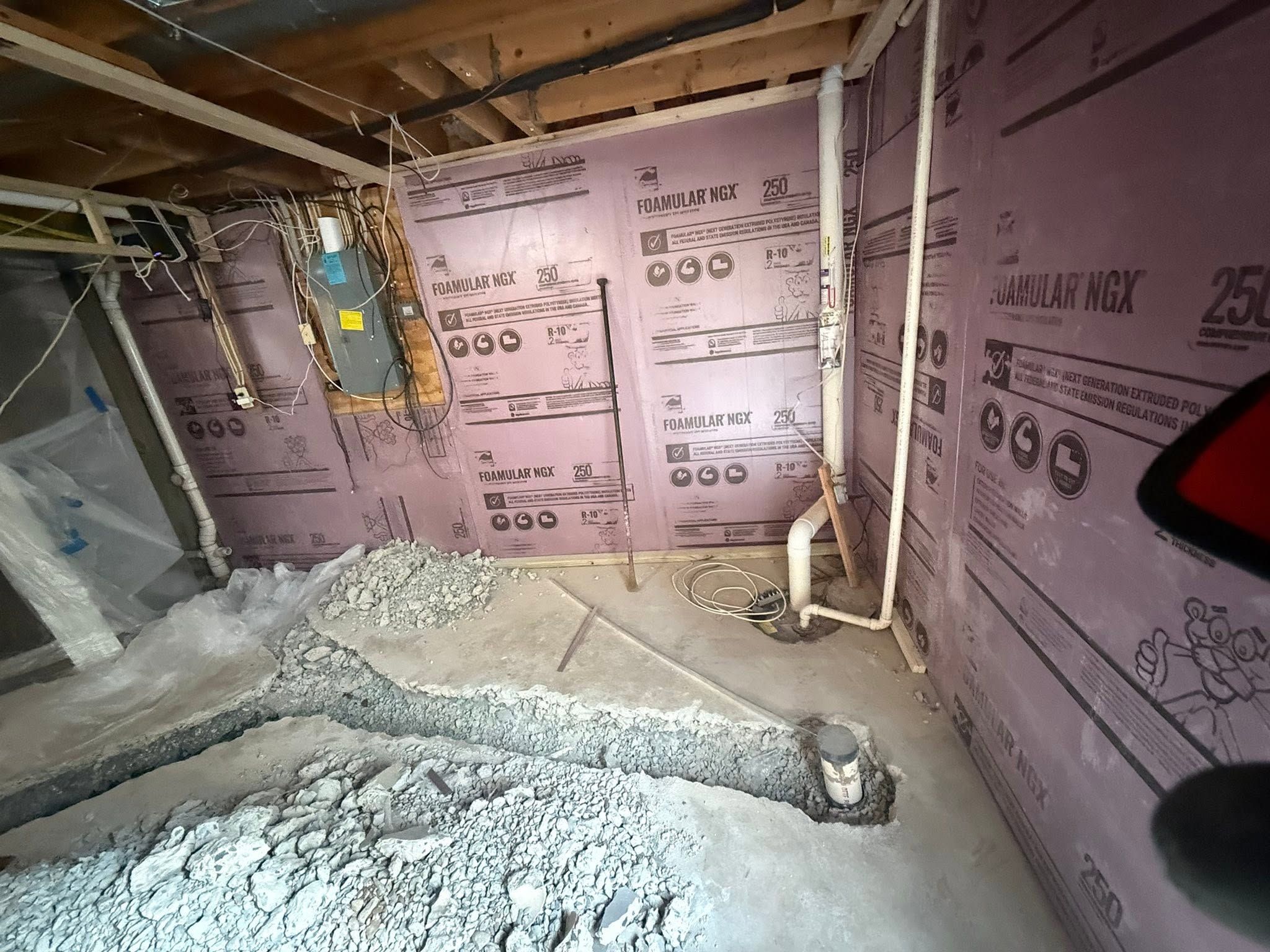 Plumbing rough-in with exposed pipes and drain lines in an unfinished basement