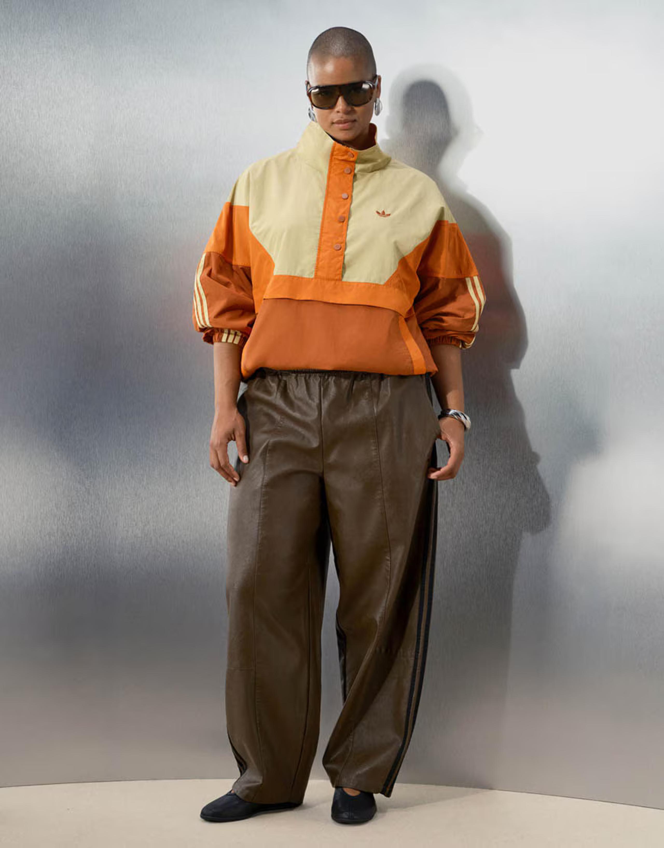 The overhead track jacket in orange and pale yellow, worn with brown leather-look track pants