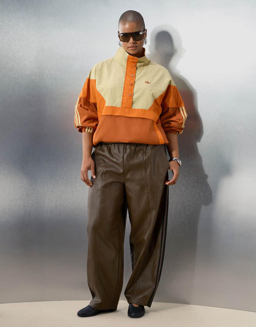 The overhead track jacket in orange and pale yellow, worn with brown leather-look track pants