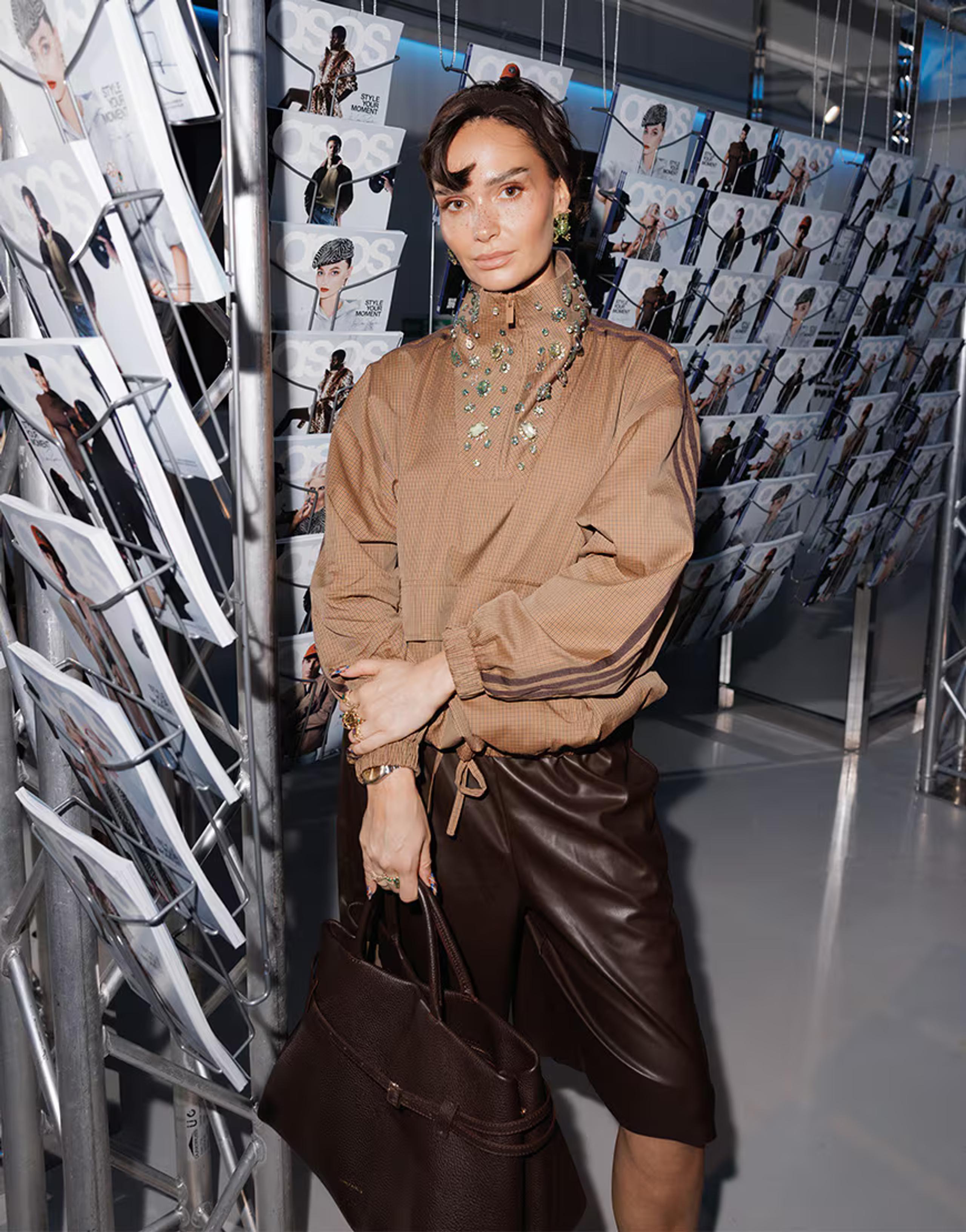 Model wearing an oversized beige snake-print adidas Originals x ASOS tracksuit with contrast three stripes, styled with pointed heels against a plain studio backdrop