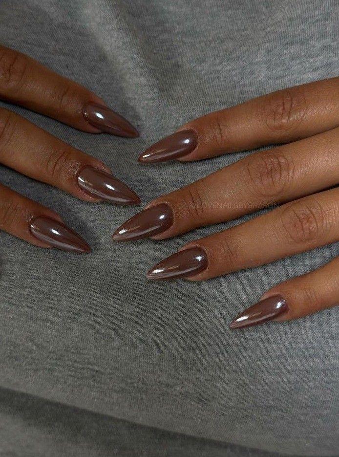 Long almond nails in a glossy mocha chrome finish against a grey jumper