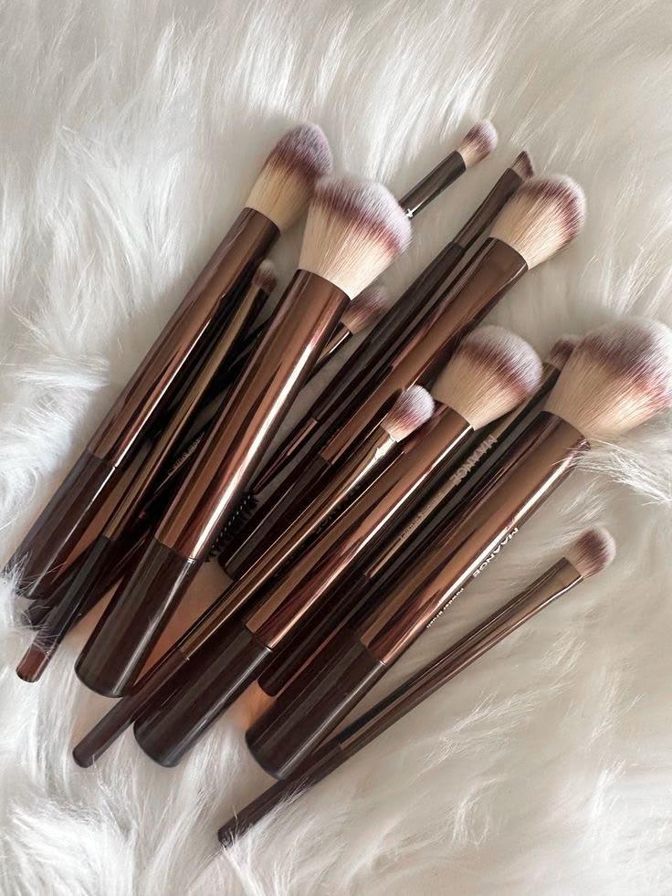 Make-up brushes, a sponge and an eyelash curler laid out on a linen cloth