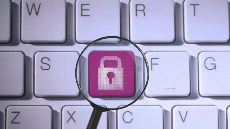 A magnifying glass focuses on a pink keyboard key displaying a white padlock icon.