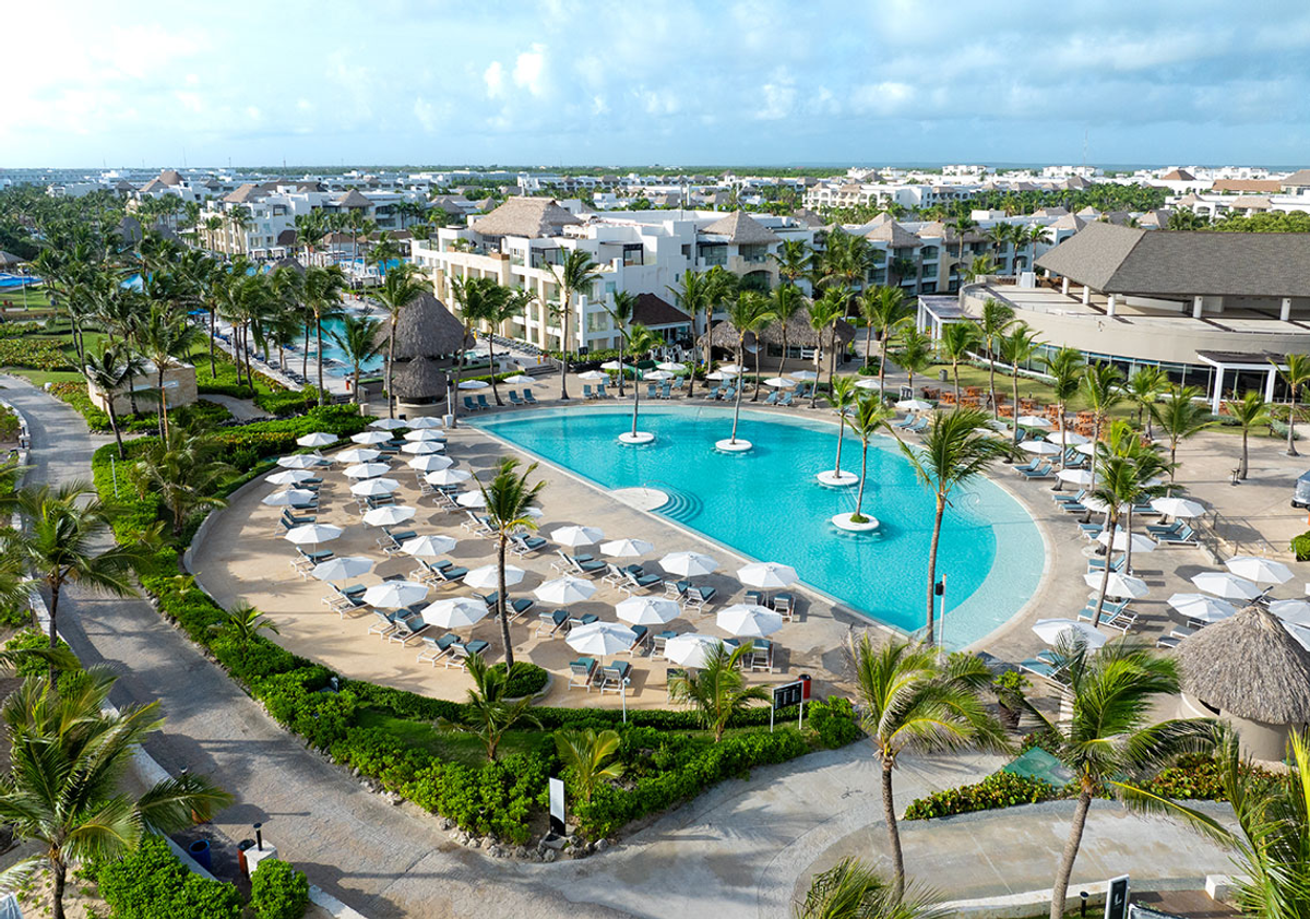 Aerial view of the Hard Rock Hotel and Casino Punta Cana featuring large outdoor swimming pools, palm trees, resort buildings, and sun loungers with umbrellas.
