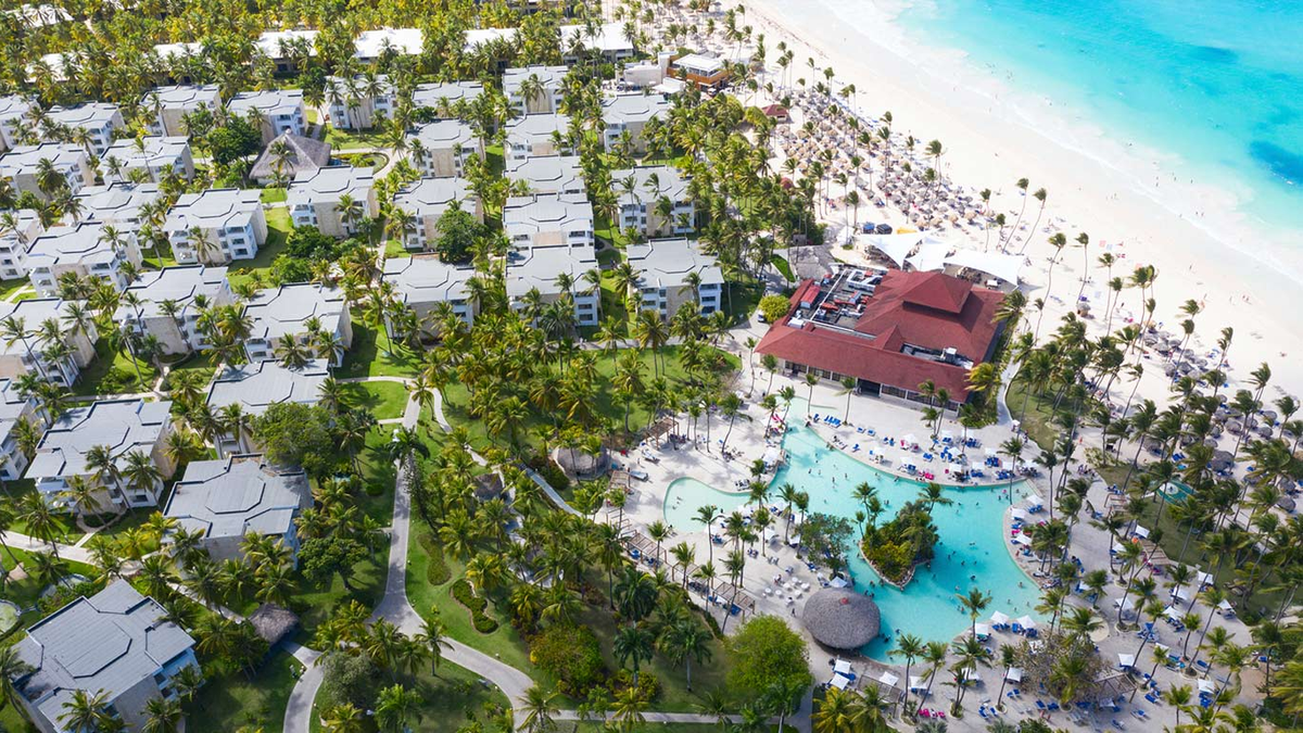 Aerial drone view of the Grand Bavaro Princess resort in Punta Cana, showing the layout of guest villas, main pool area with palm trees, and beachfront.