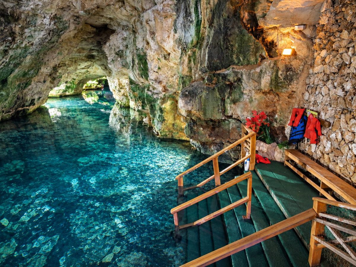 Pasarela de madera junto a aguas turquesa en el interior de una cueva
