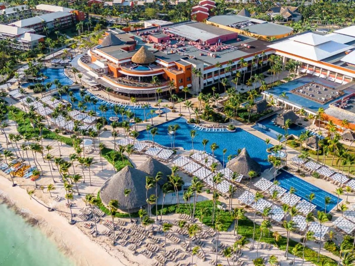 Aerial view of Barceló Bávaro Palace resort, featuring expansive swimming pools, palm trees, sun loungers, and beachfront areas along the coast