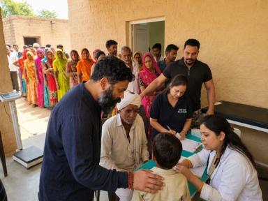Ishan Shivanand distributing supplies during a rural community outreach program