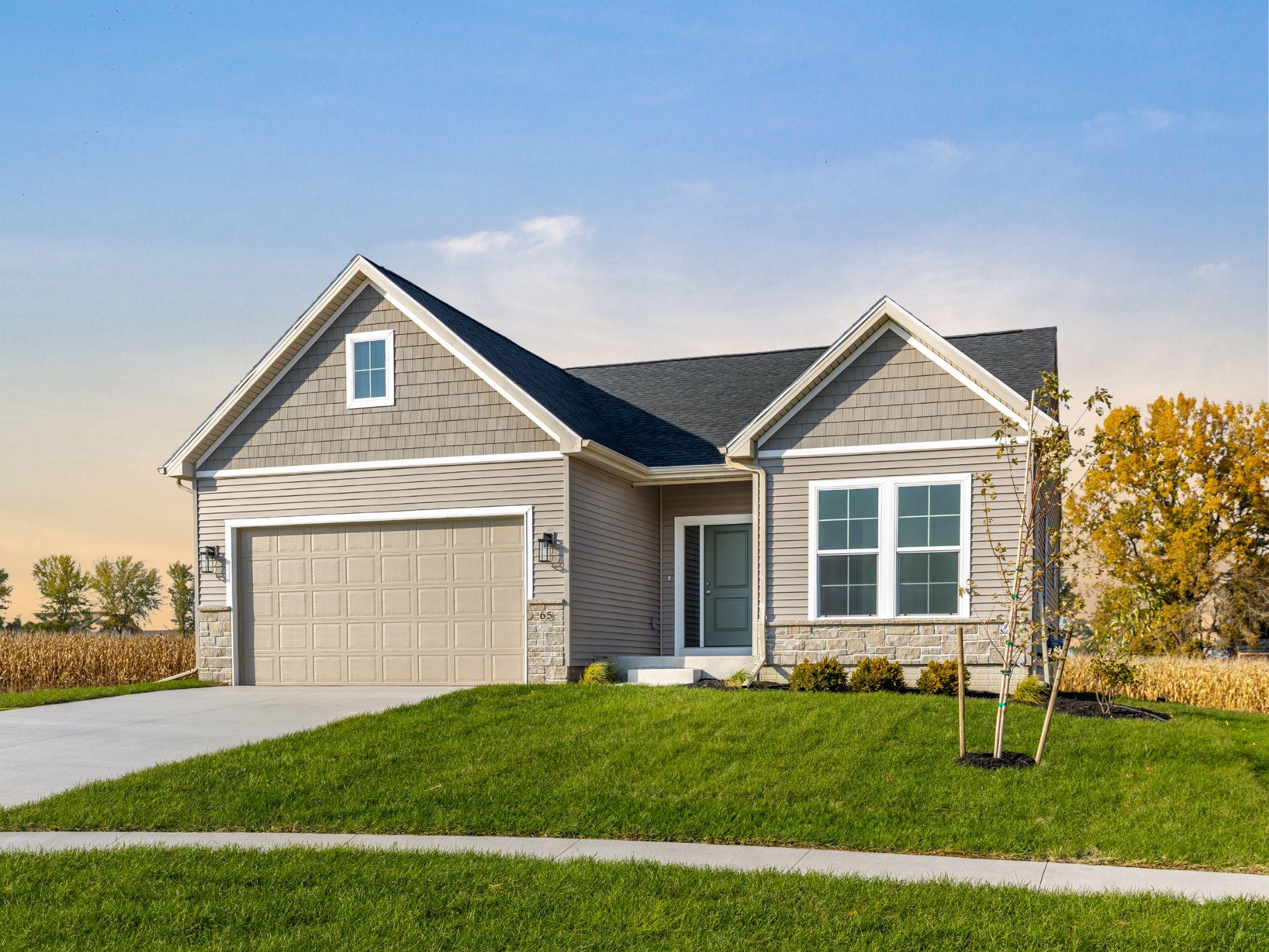 A single-story home with a one car garage, tan exterior and green door.