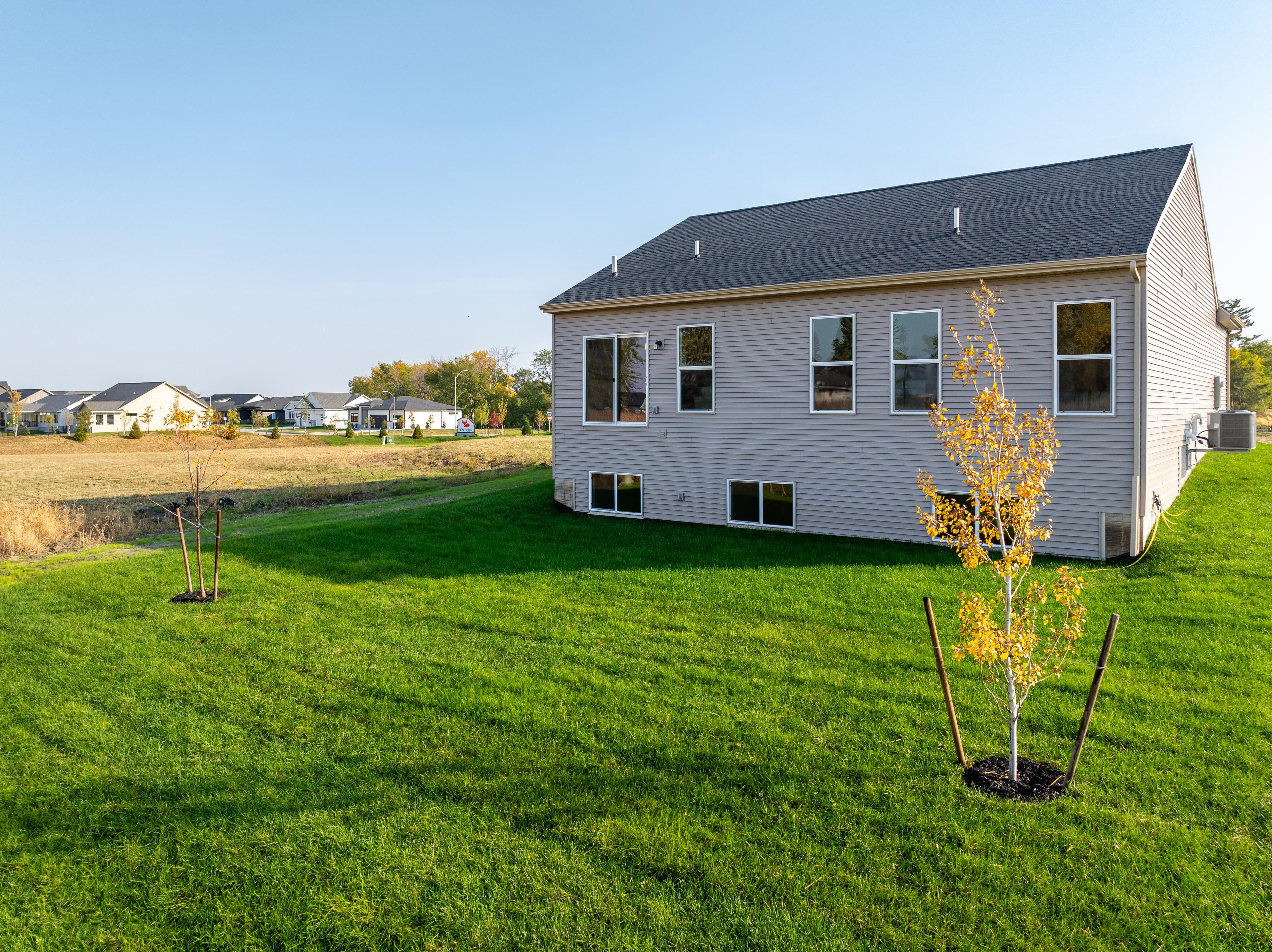 An outdoor photo of a back yard to a home featuring white siding and a gray roof. 