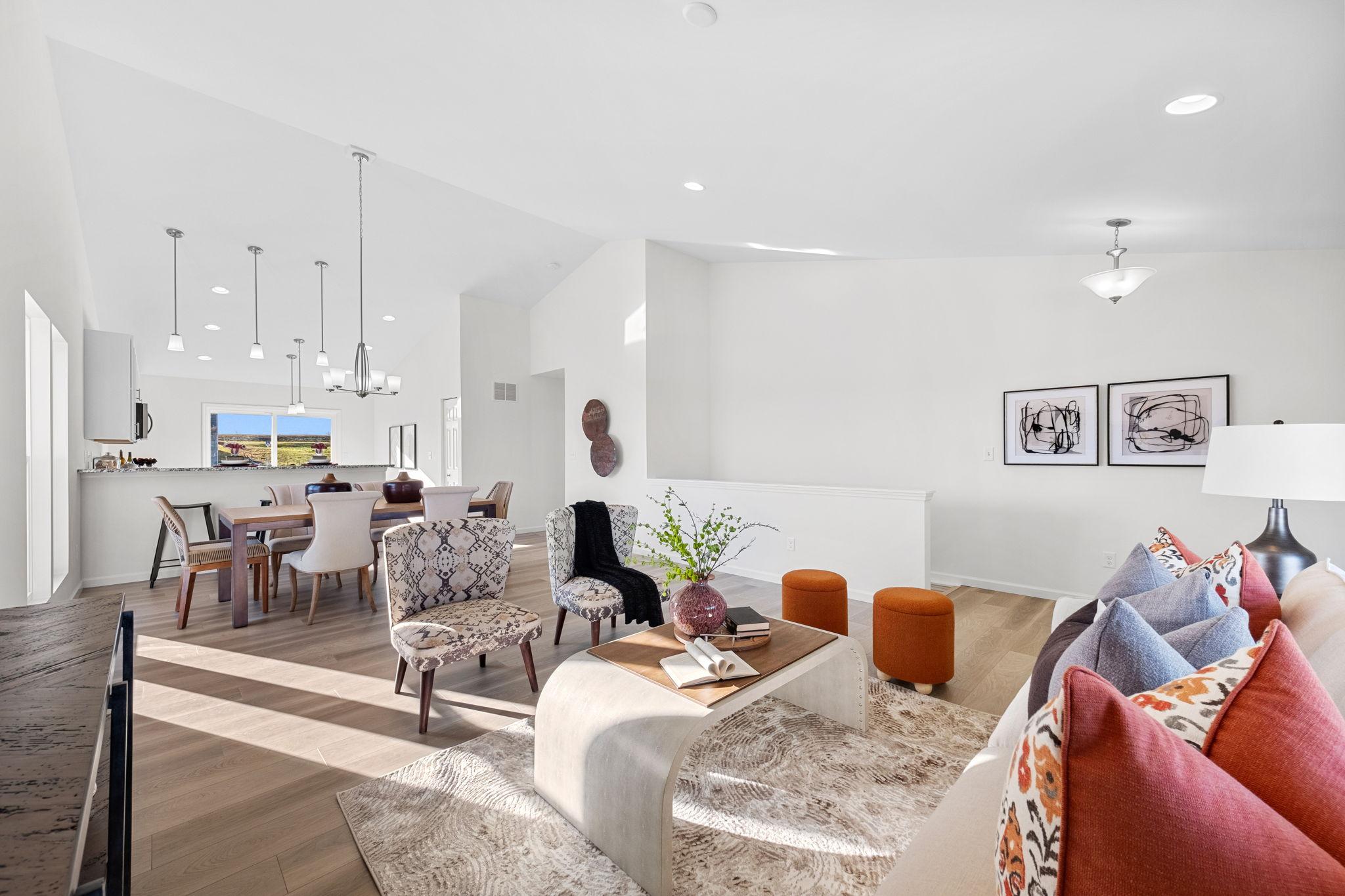 An open concept living room that opens up to a kitchen with tall, cathedral ceilings.