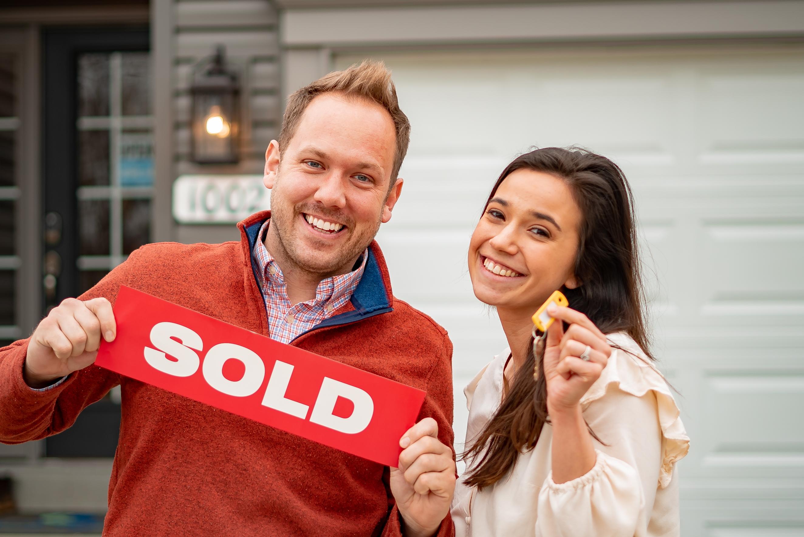 People Holding A Sold Sign