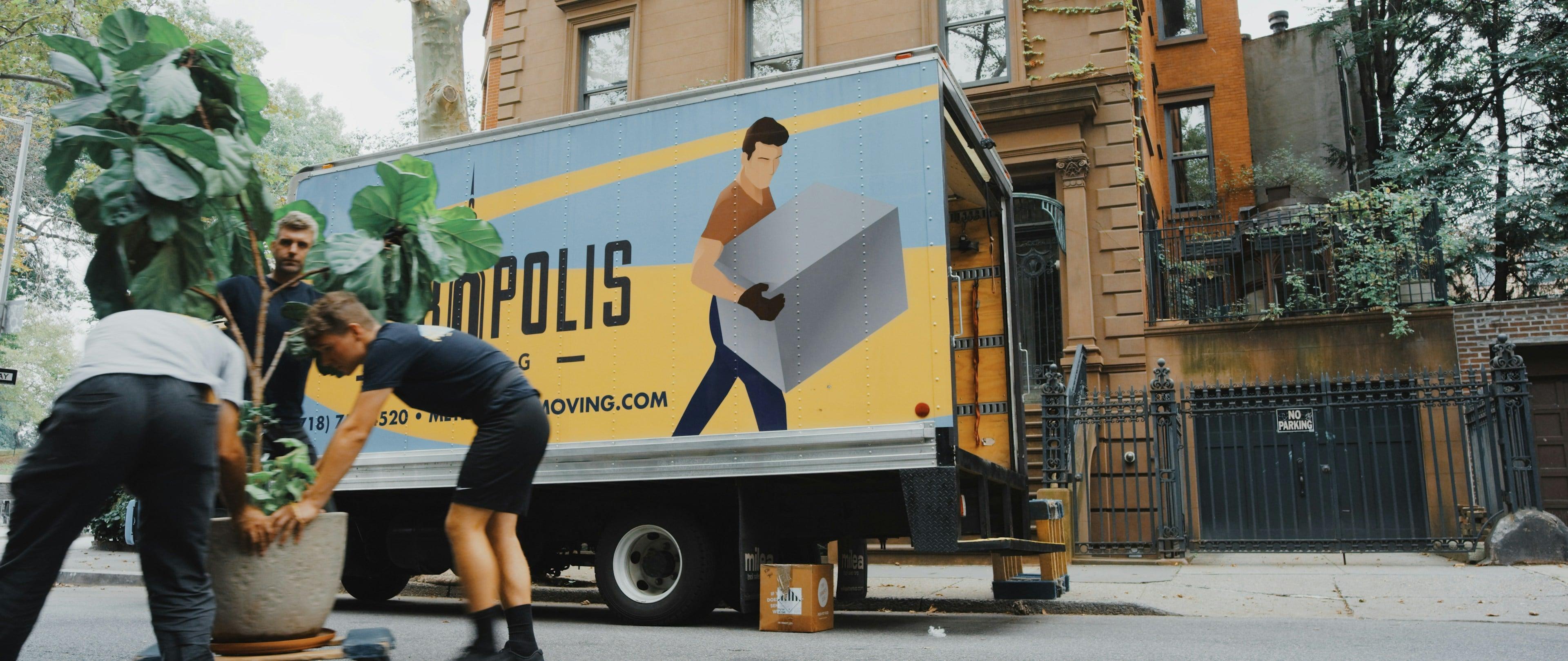 A moving truck with a colorful advertisement and a person walking beside it.