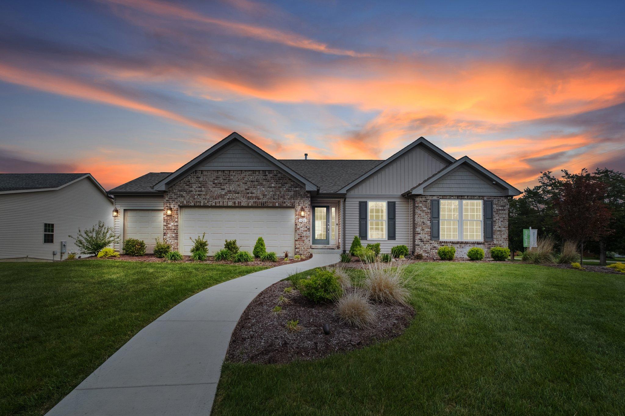 Beautiful Gentry Homes ranch-style house at sunset, featuring a well-manicured lawn, a modern stone and siding exterior, and a welcoming front path in a serene Iowa community.
