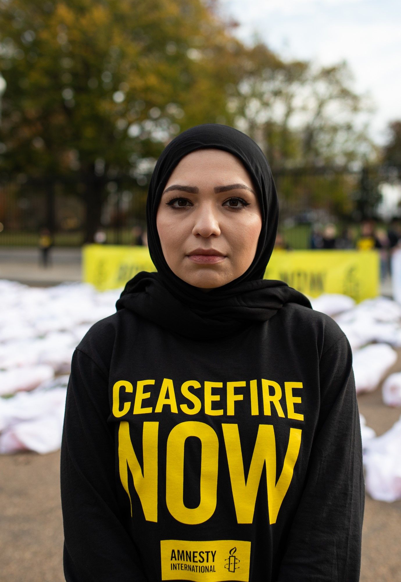 An Amnesty supporter stands wears a sweater reading "ceasefire now"