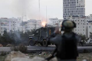 An Israeli border policeman watches as tear gas cannisters are fired
