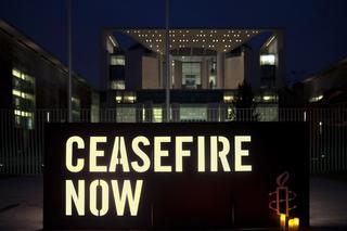 Amnesty supports hold a vigil with signs that read "ceasefire now" outside the https://amnestynz.sharepoint.com/:w:/s/FileShare/EZc0Q3d1r_FHinlpeOBprkcBjlwNc-pWBGkZ45Ph4fe9eg?e=WwWD1KChancellery in Berlin on 18 December 2023. 