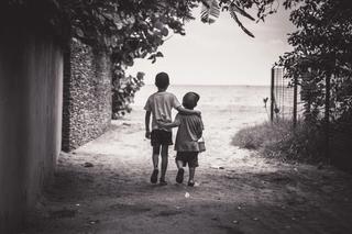 two small children walk towards a beach