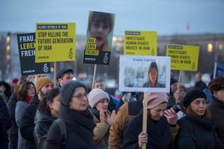 a crowd of people holding signs calling for the end of executions in Iran