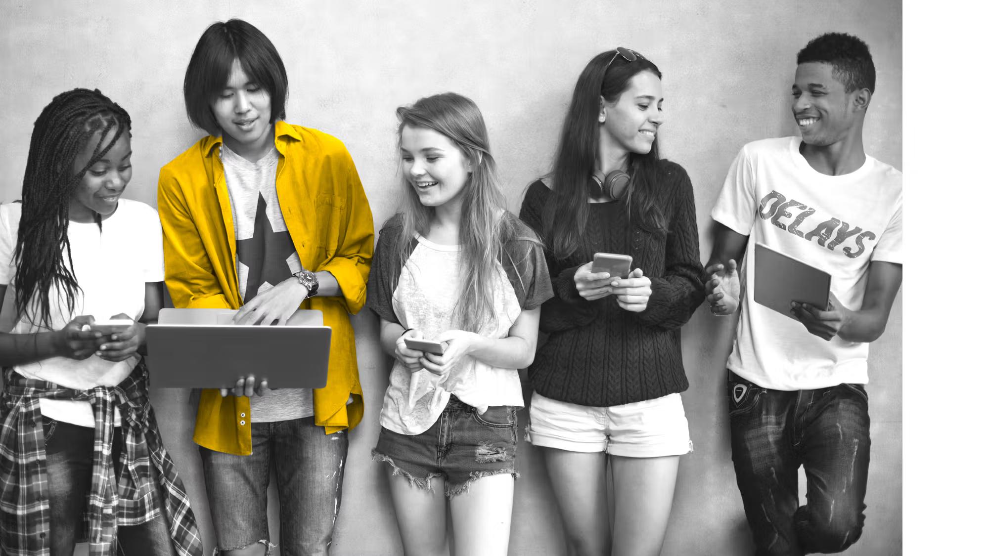 teens standing in a row interacting with devices