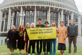 A group of people stand outside the NZ Parliament