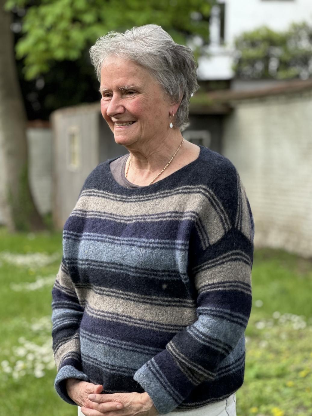 Cecile de Ryckel stands with her arms in front of her, smiling.