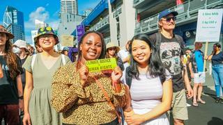 people at a protest holding a sticker that reads "climate justice = human rights"