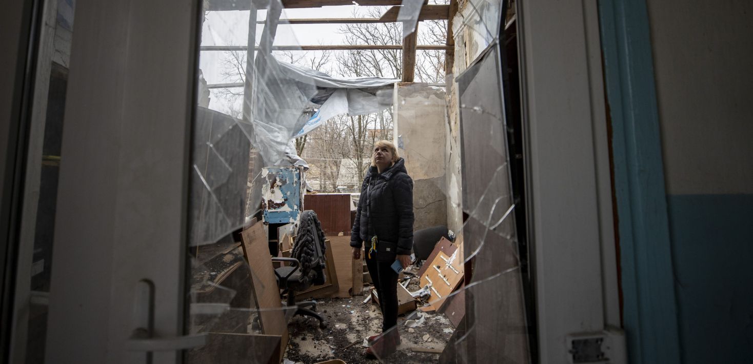 A woman stands in a damaged building.