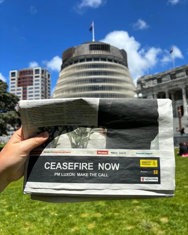 An image of a newspaper held in front of the Beehive building in Wellington