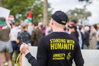 A view of the back of a man wearing a black cap and an Amnesty International t-shirt