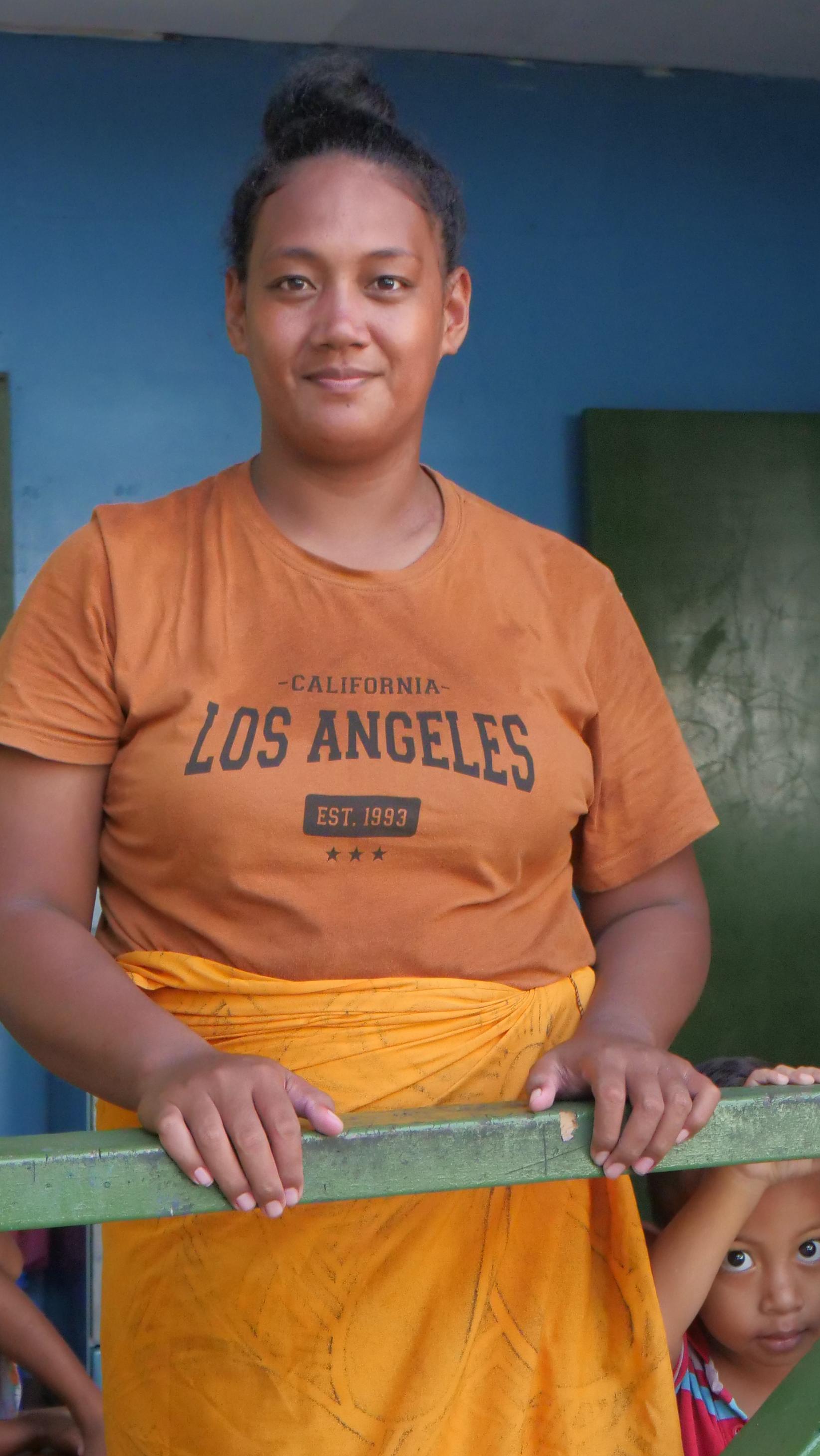 a woman in Tuvalu standing at a balcony with her children