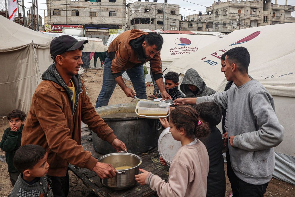 Volunteers distribute rations of red lentil soup to displaced Palestinians in Rafah in the southern Gaza Strip