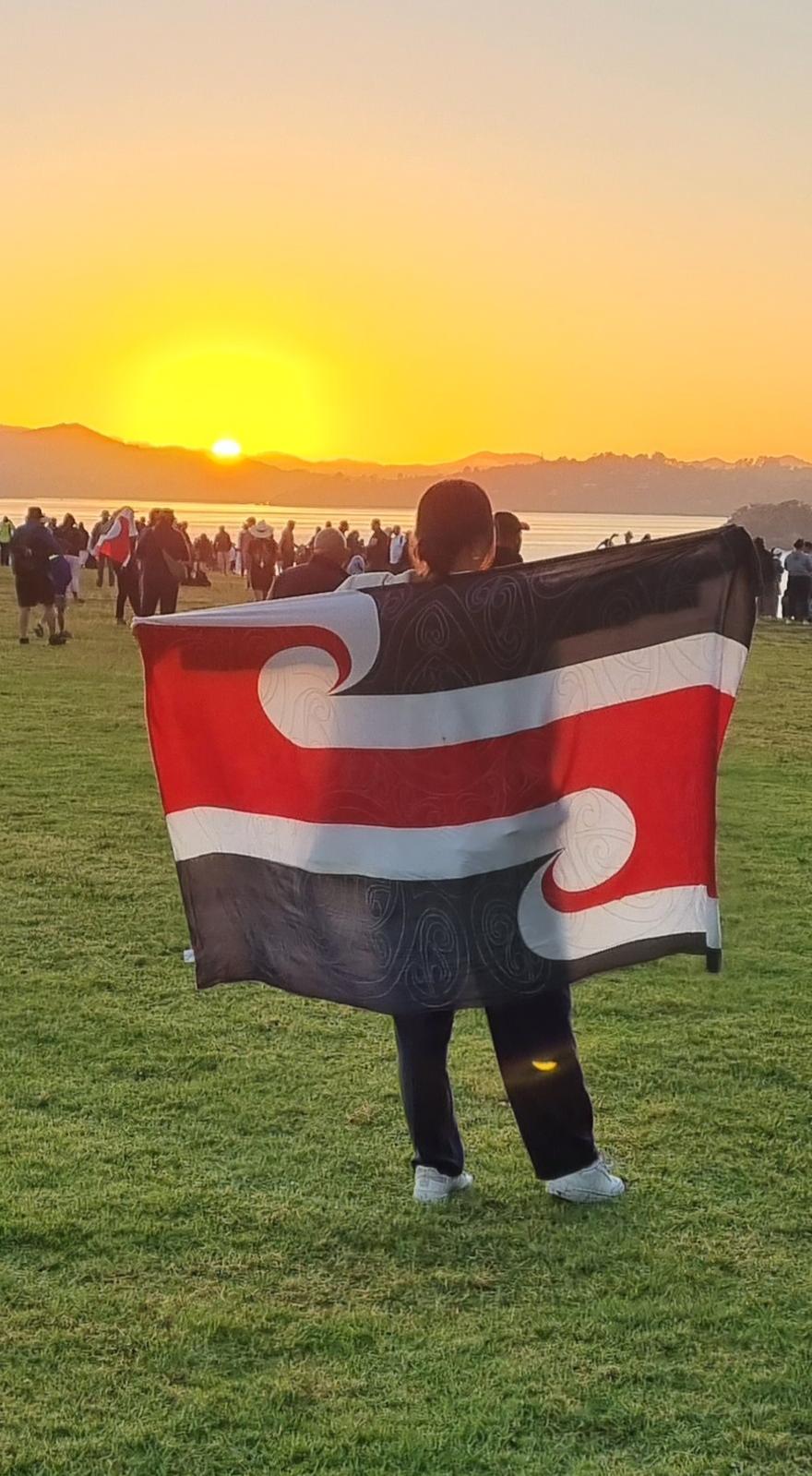 A person holds a tina rangatiratanga flag