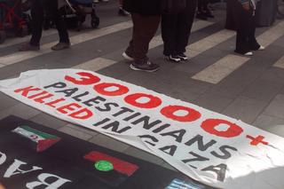 A sign on the floor reads "30000+ palestinians killed in gaza"