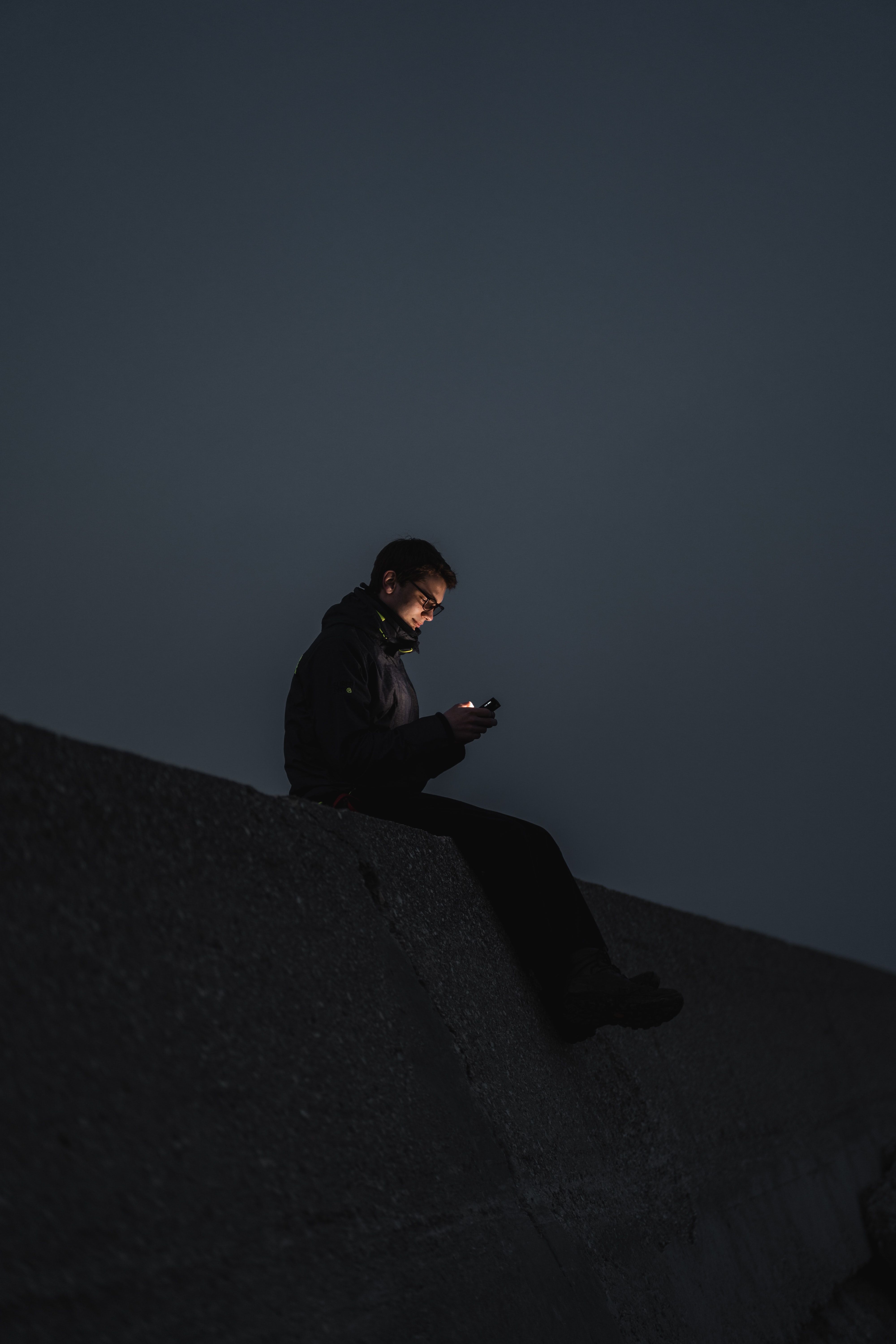 person sitting on wall using phone