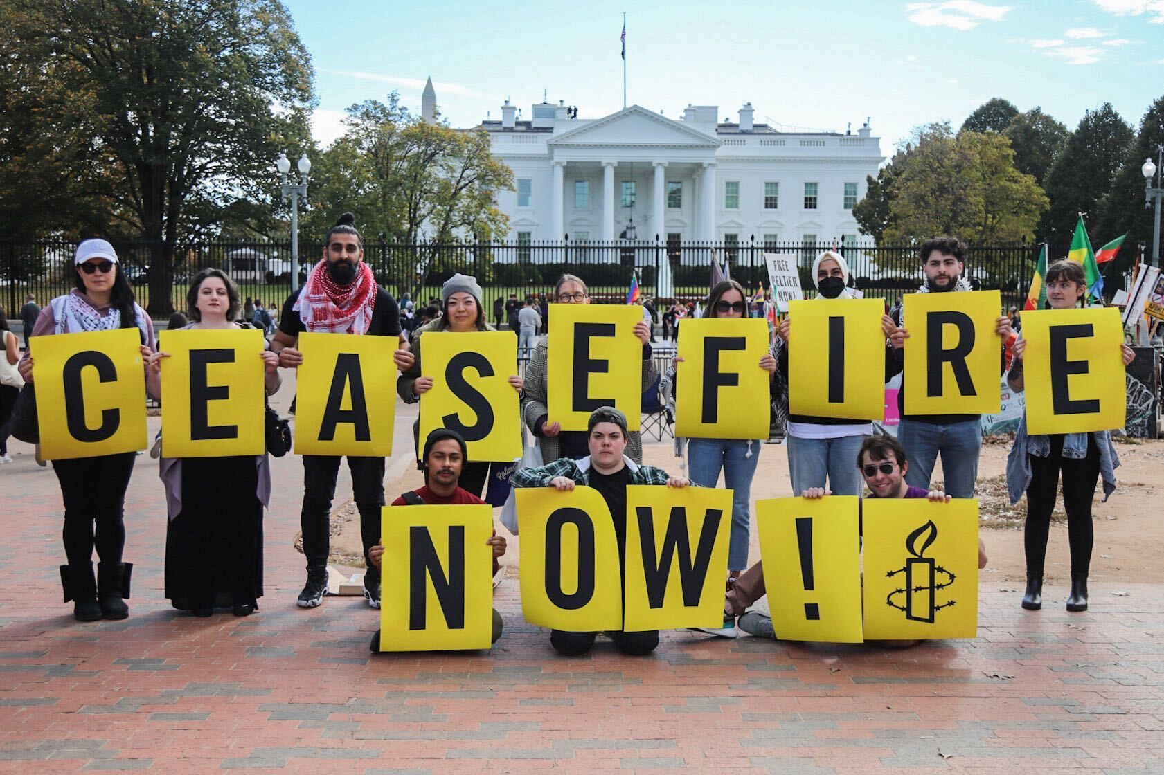 Amnesty supporters hold signs that spell out "ceasefire now!"