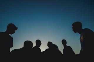 a group of young people stand against a dark blue sky
