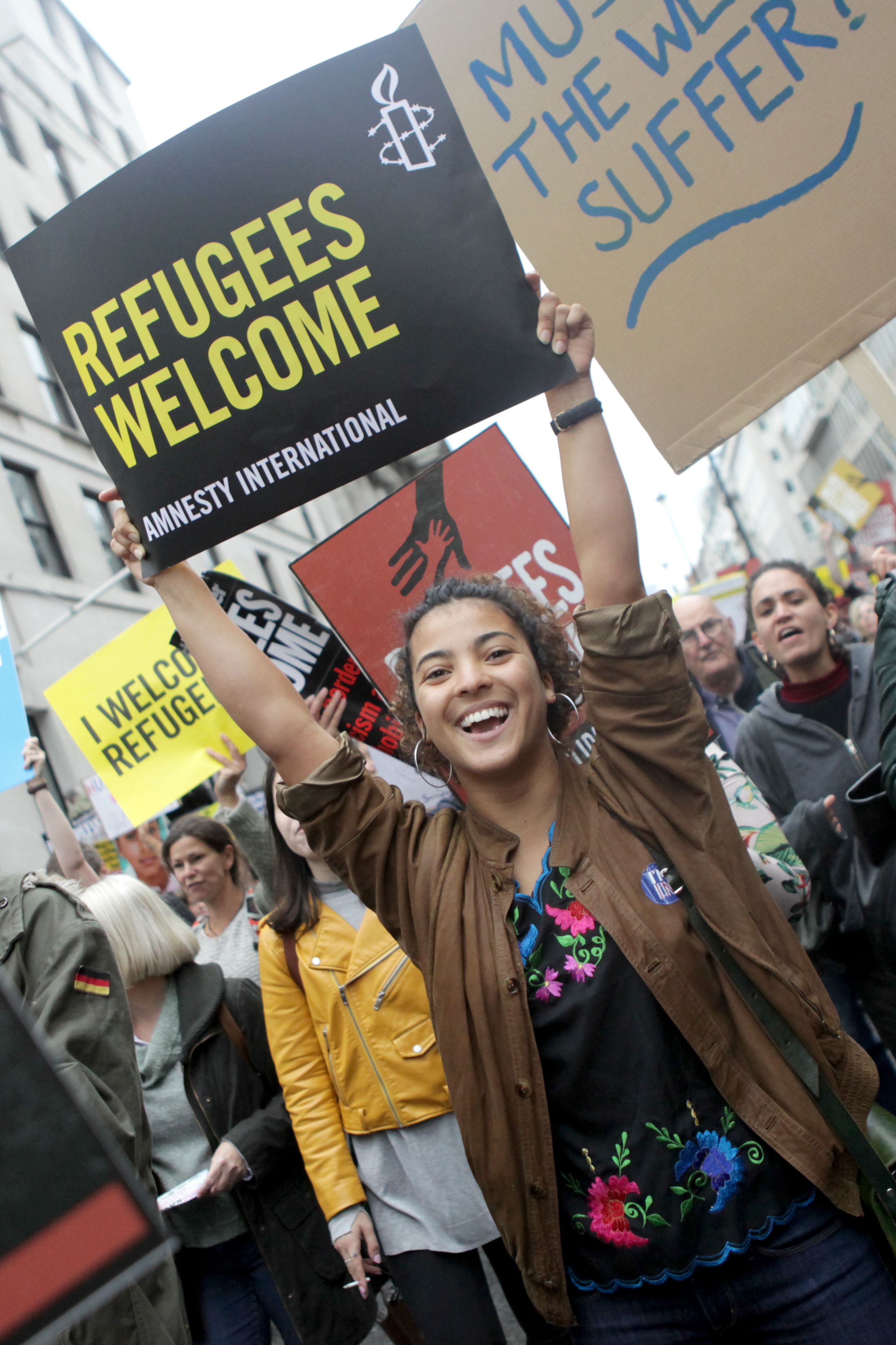 a person holds a sign reading "refugees welcome"
