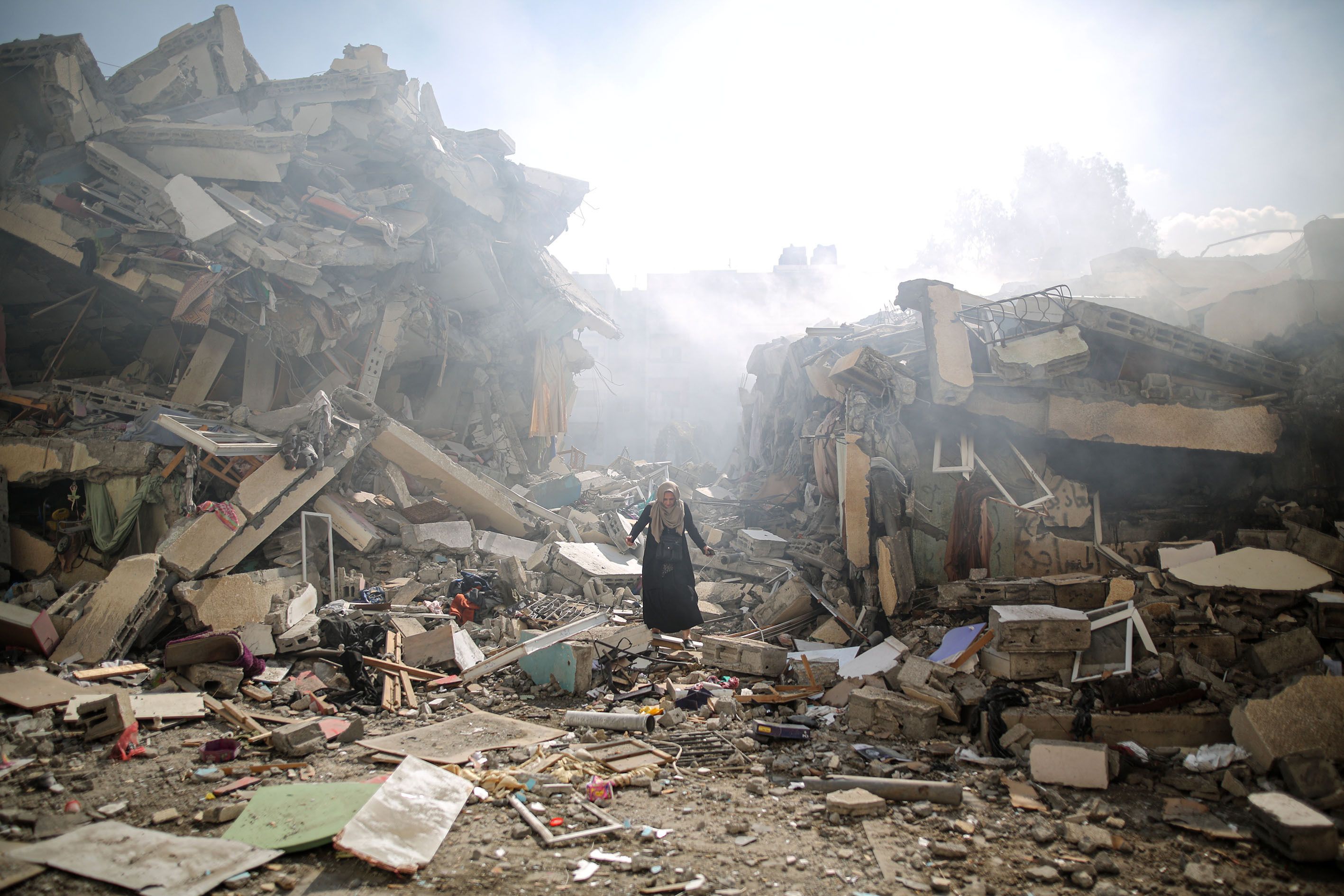 A woman walks through the rubble of residential buildings after Israeli airstrikes at al-Zahra neighborhood in Gaza Strip.