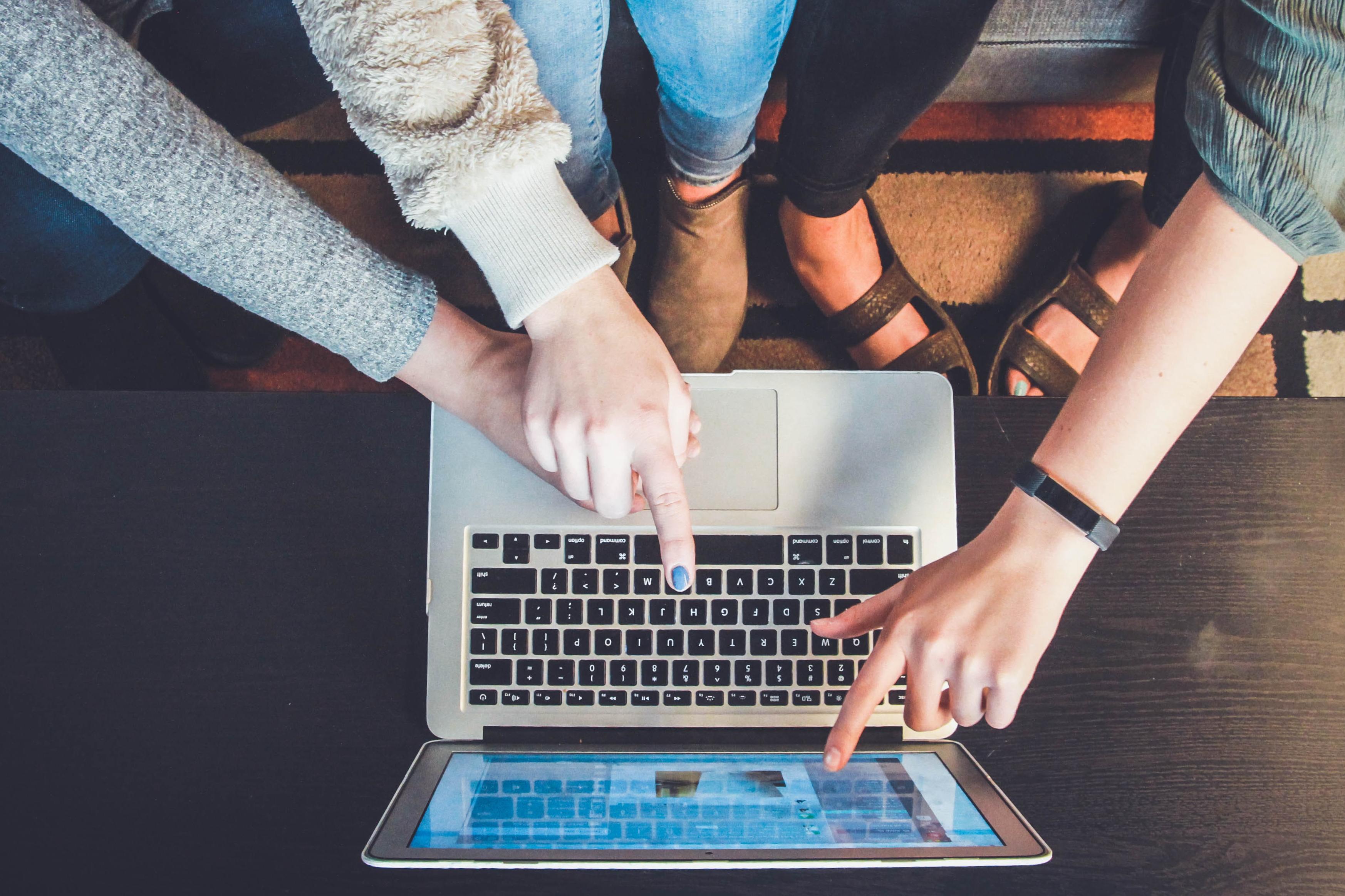 women point at a laptop