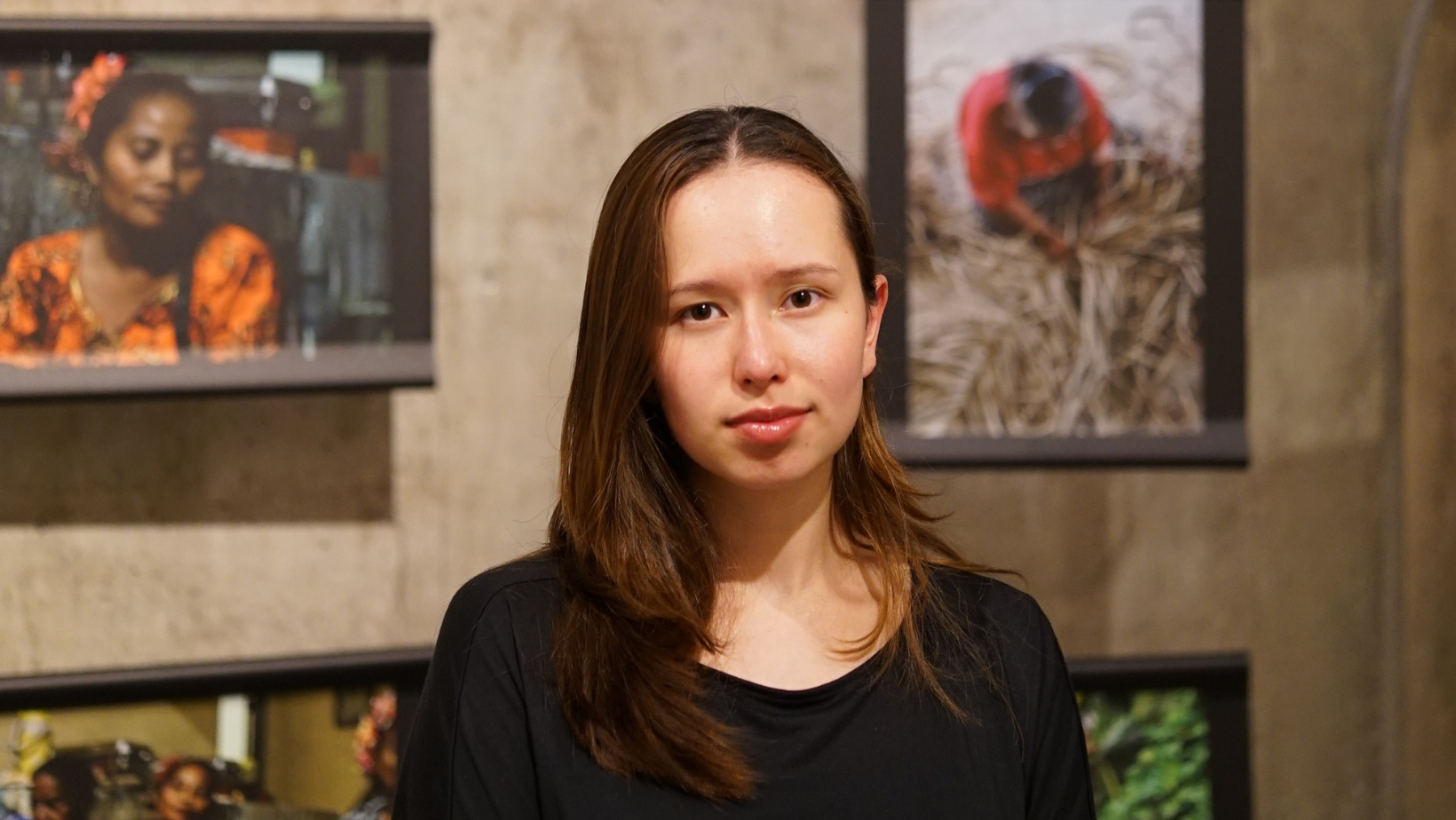 A woman stands in front of pictures on a wall