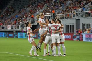 a group of women football players celebrate in a huddle