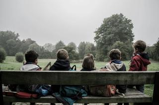 A group of children sit on a bench in a park