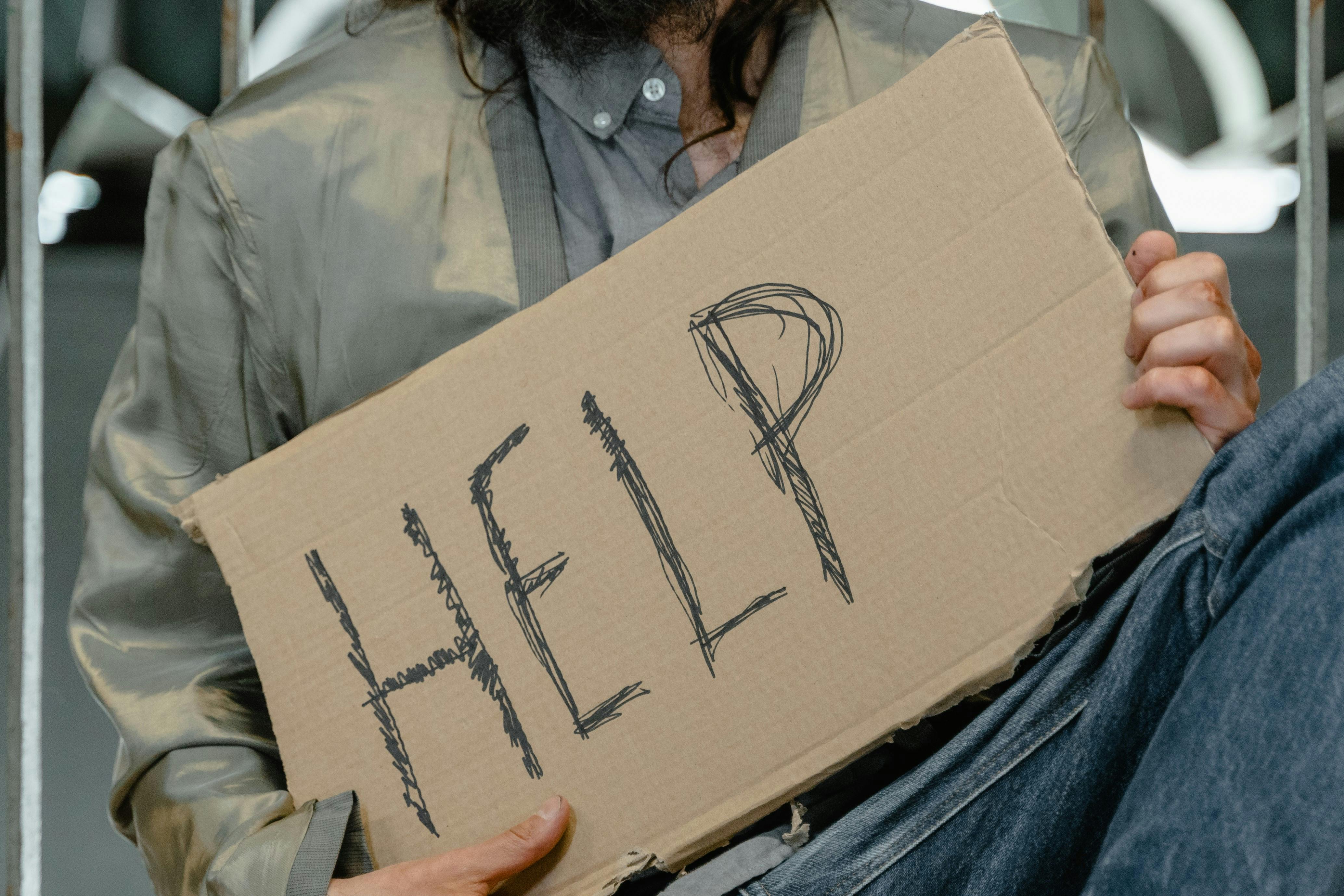Homeless man holding a help sign