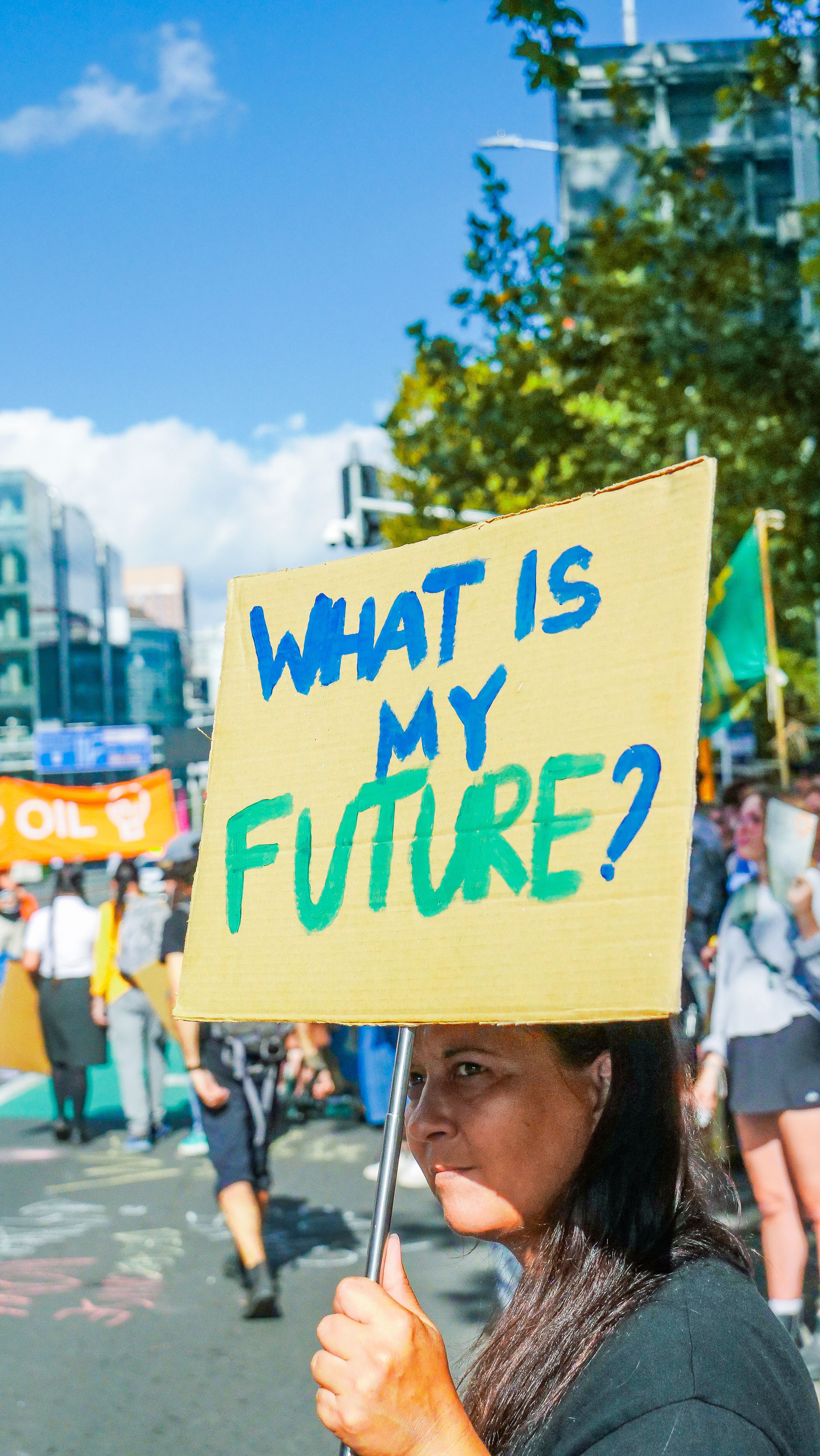 A person at a protest holds a sign that reads "what is my future?"