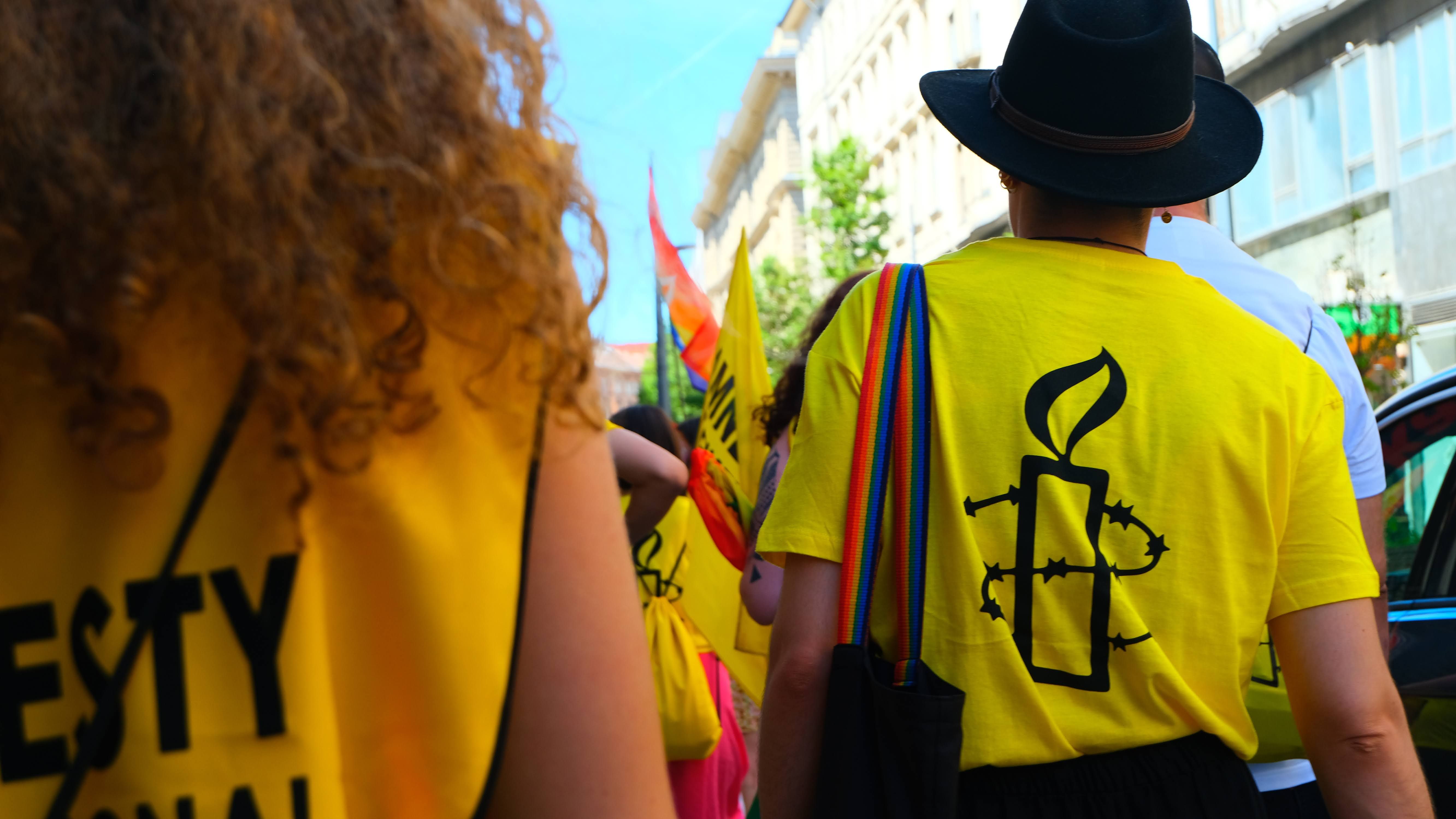 the back of two protesters walking and wearing Amnesty t shirts