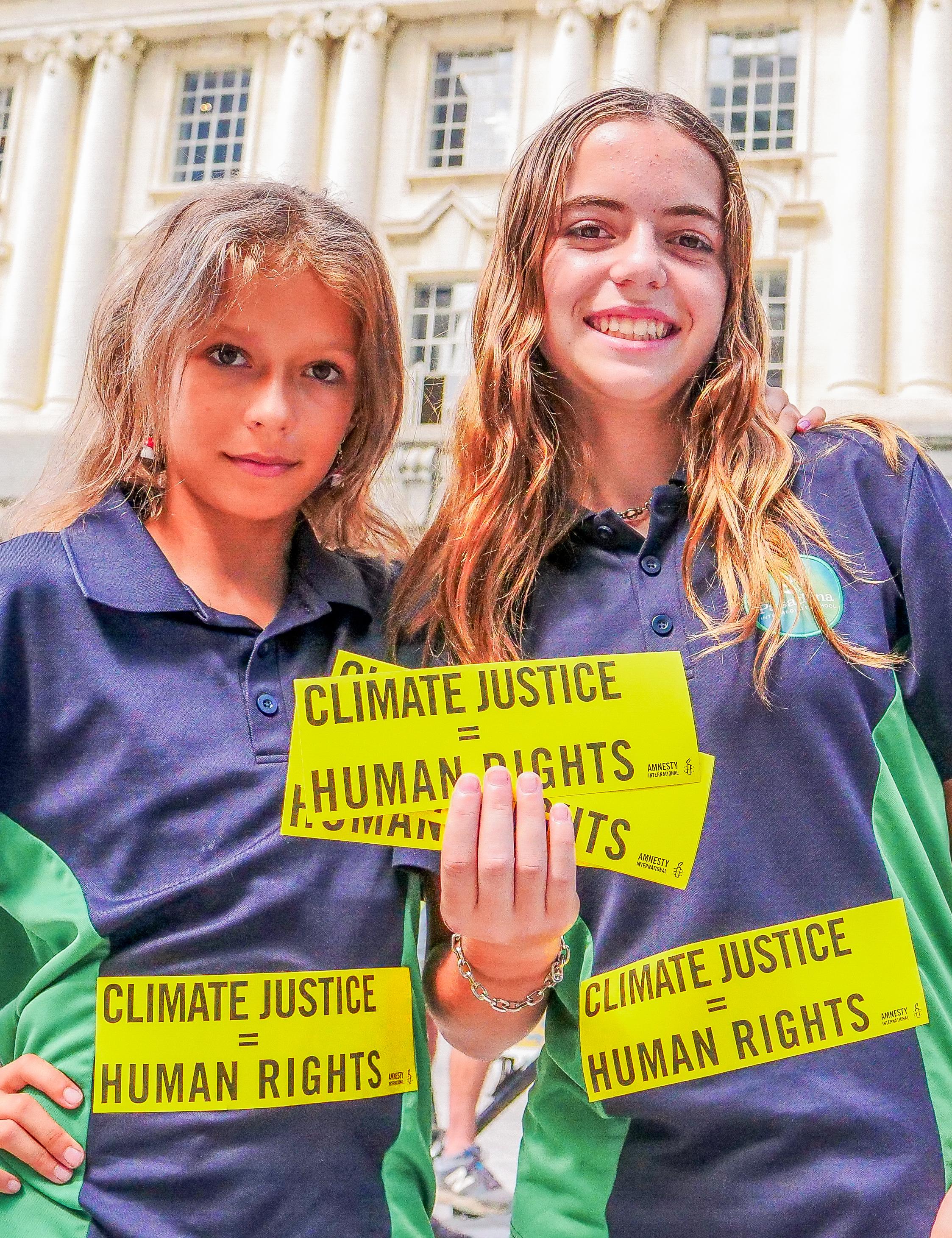 Two young people holding stickers which read "climate justice = human rights"